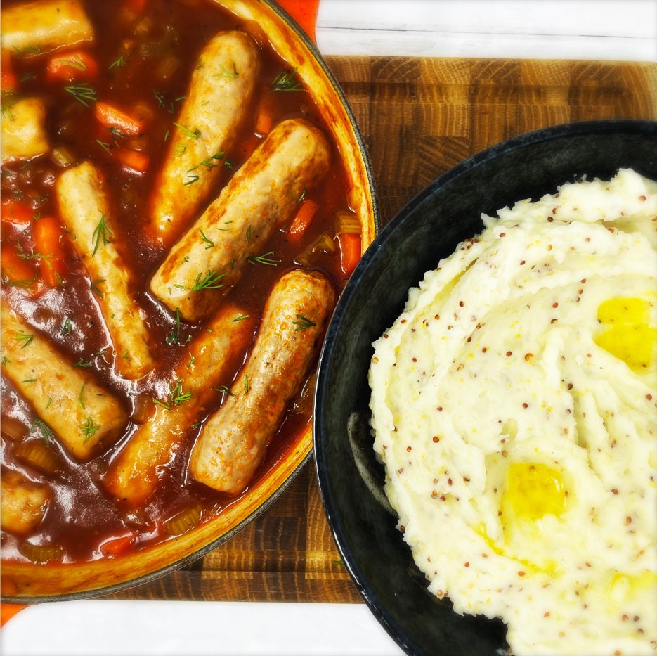 easy sausage casserole served in a skillet pan next to a bowlful of mustard mash