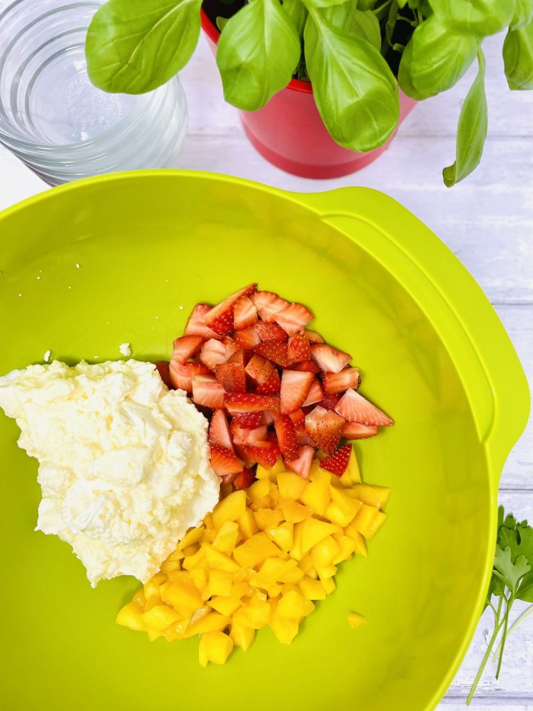 whipped vanilla cream in a bowl with strawberry and mango slices