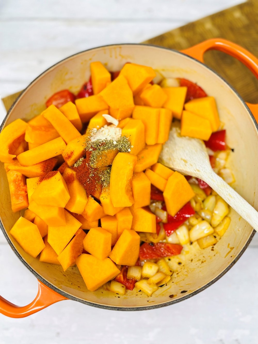 making butternut squash chilli in a skillet pan being stirred with a wooden spoon
