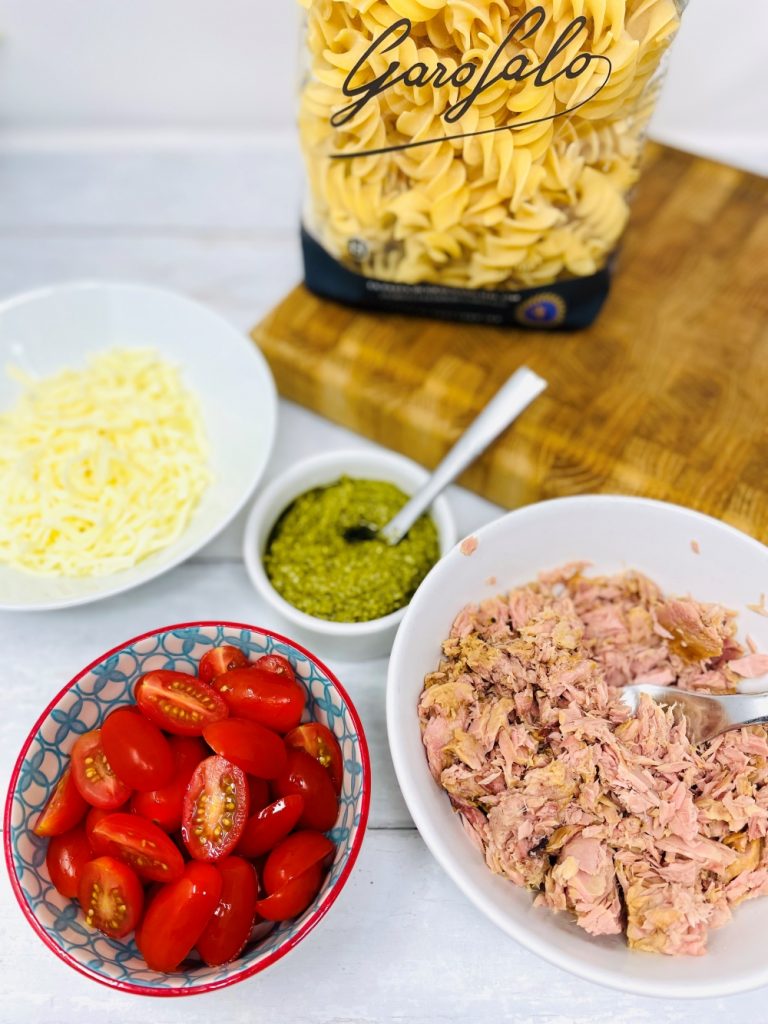 tuna pesto pasta ingredients on a whit table - pasta, mozzarella, tuna, cherry tomatoes and pesto