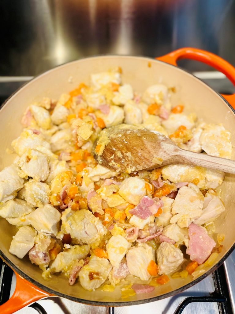 diced chicken breast being fried with vegetables in a skillet pan