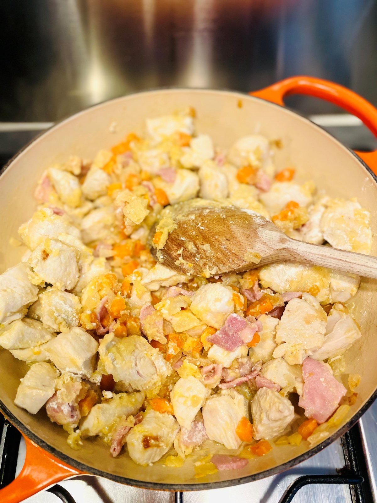 diced chicken breast being fried with vegetables in a skillet pan