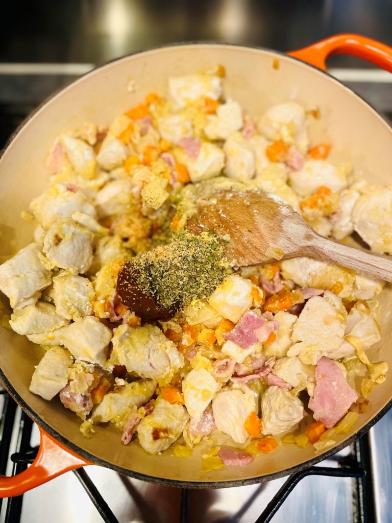 stock pot, herbs and spices added to fried chicken and vegetables in a skillet pan