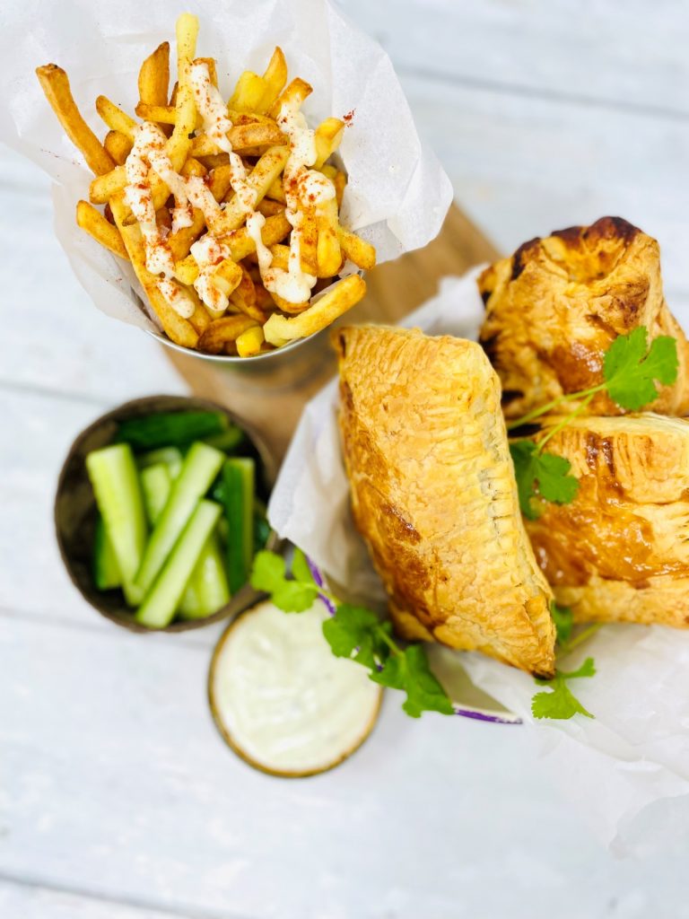 chicken tikka pasty in a serving bowl with bucket of French fries and cucumber sticks with dip