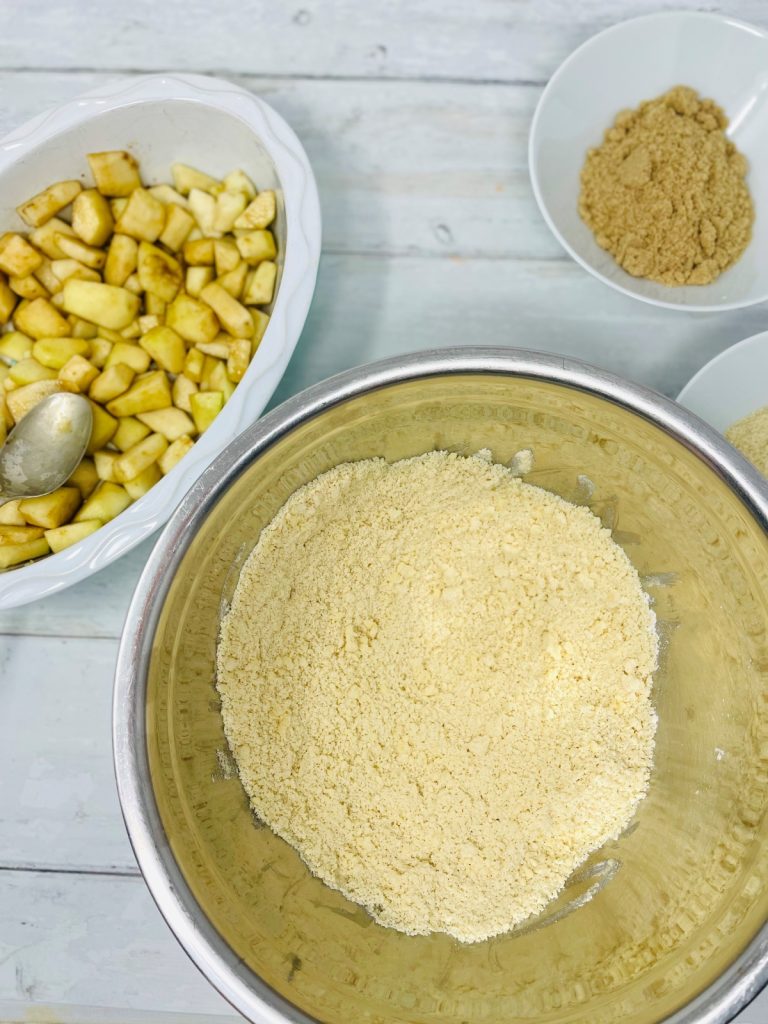 crumble topping in a mixing bowl next to an oven proof dish filled with chopped pears