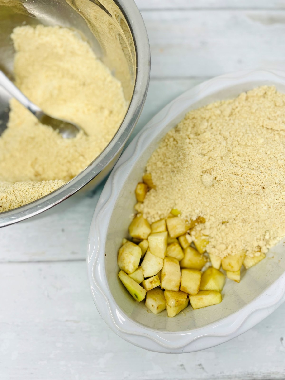 crumble topping being scattered over chopped pears in an ovenproof dish