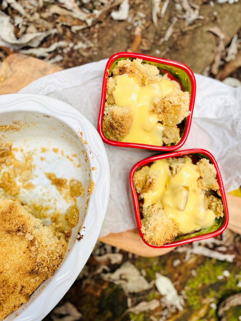 pear crumble with custard served in red bowls on a wooden board in the autumn garden