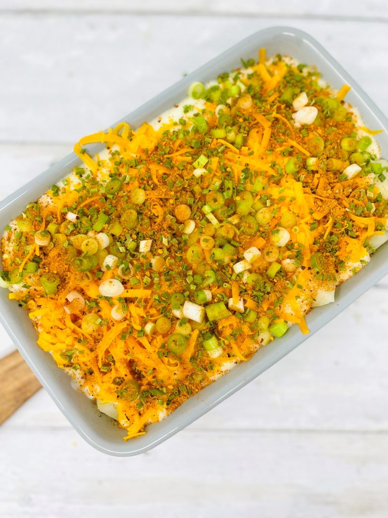 Tray of cheesy potatoes topped with chipotle sauce cheese spring onions and chives